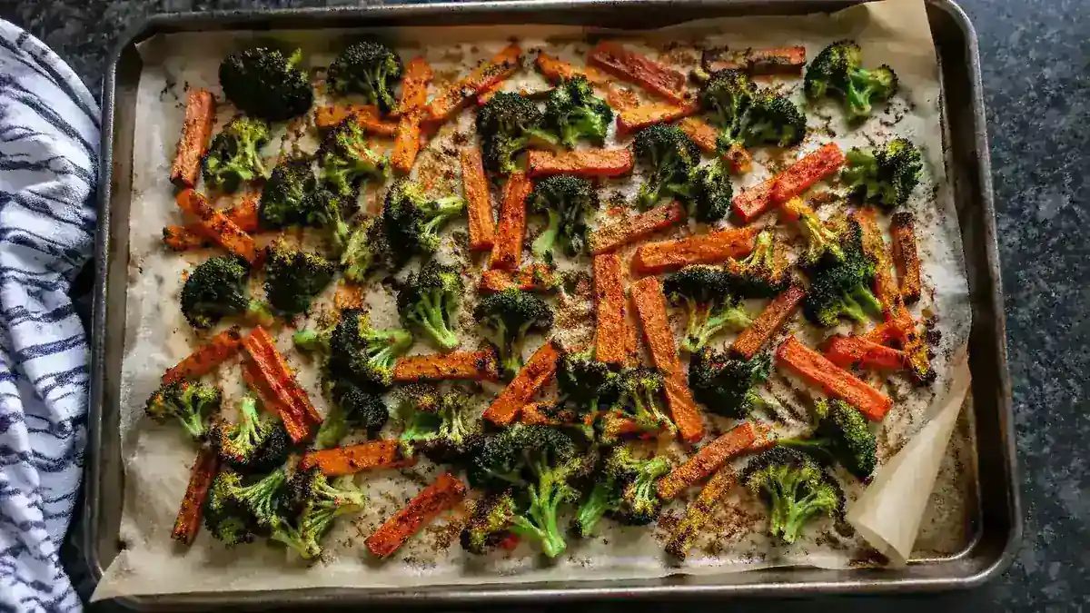 Sheet pan with roasted broccoli and carrots on parchment paper, edges slightly charred